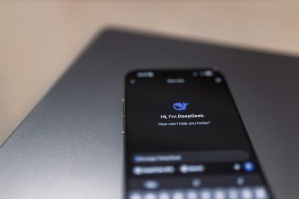 Smartphone exibindo uma interface de assistente de inteligência artificial sobre um laptop.