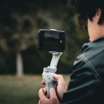 Pessoa utiliza um estabilizador de smartphone ao ar livre para gravar um vídeo com mais estabilidade.