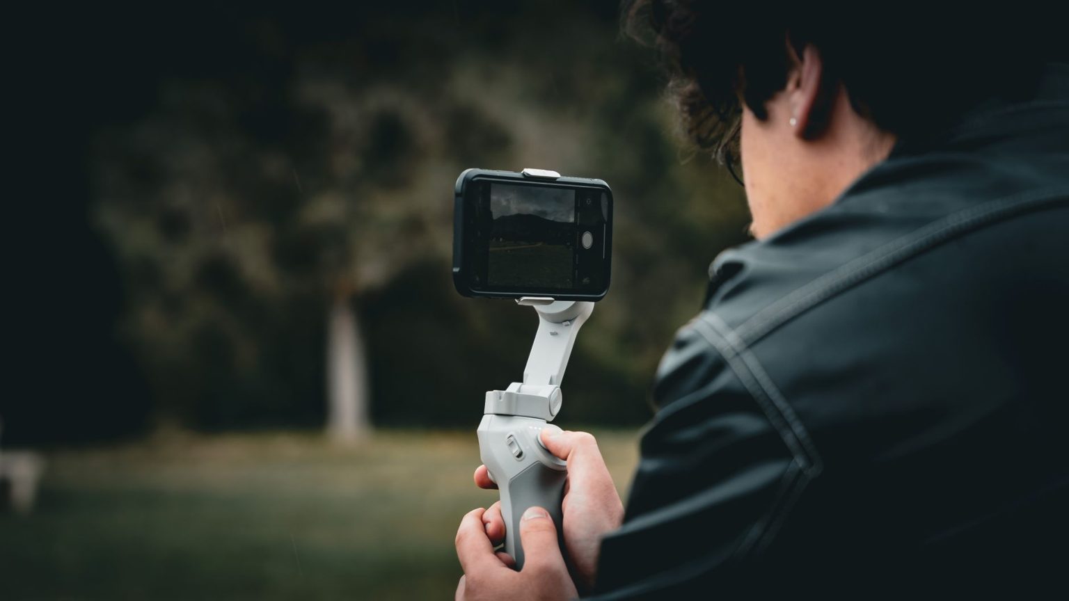 Pessoa utiliza um estabilizador de smartphone ao ar livre para gravar um vídeo com mais estabilidade.