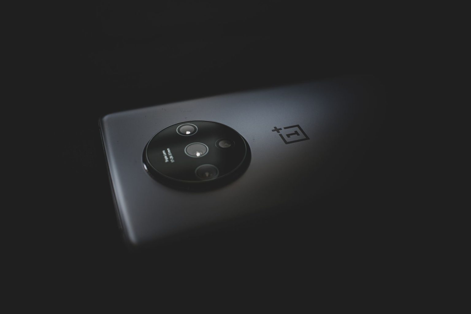 Detalhe aproximado do módulo de câmeras traseiras de um smartphone moderno sobre fundo escuro.