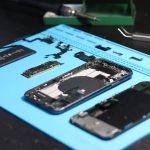 Smartphone desmontado sobre uma bancada, cercado por ferramentas de reparo.