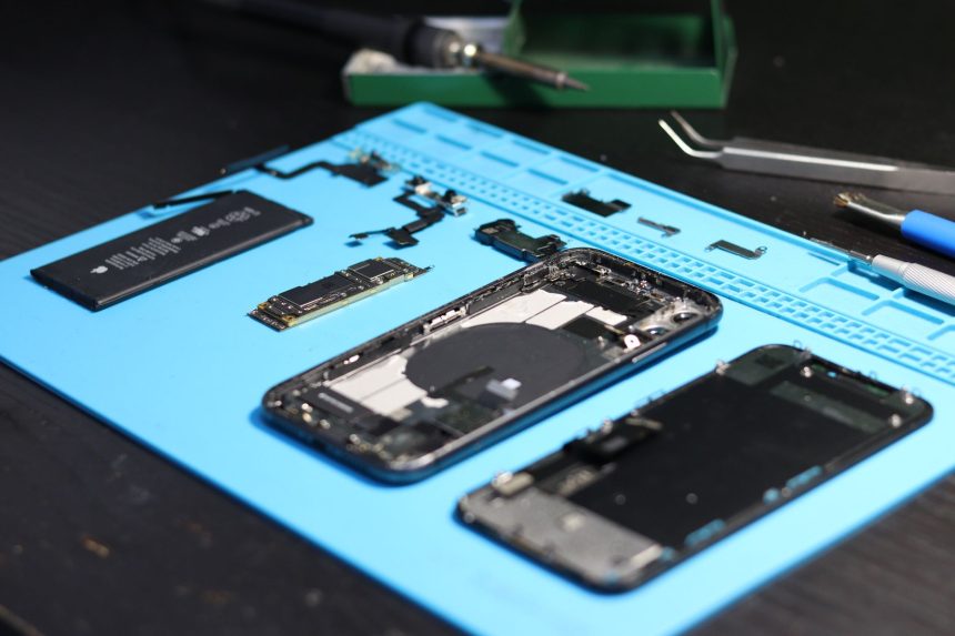 Smartphone desmontado sobre uma bancada, cercado por ferramentas de reparo.