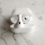 Fones de ouvido sem fio brancos em estojo de carregamento aberto sobre uma superfície de mármore