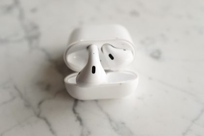 Fones de ouvido sem fio brancos em estojo de carregamento aberto sobre uma superfície de mármore