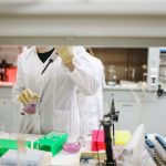Cientista de jaleco manuseia amostras em um laboratório moderno.