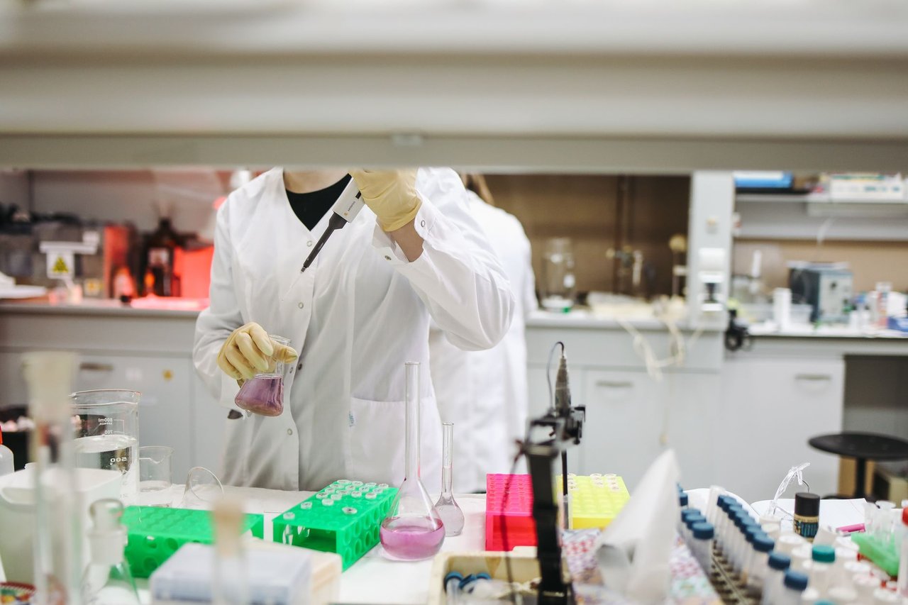 Cientista de jaleco manuseia amostras em um laboratório moderno.
