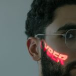 Homem usando óculos enquanto a palavra “CYBER” é projetada sobre seu rosto.
