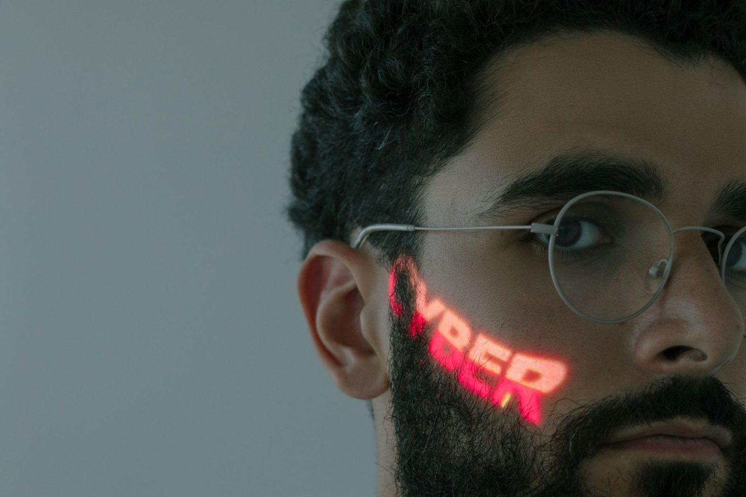 Homem usando óculos enquanto a palavra “CYBER” é projetada sobre seu rosto.