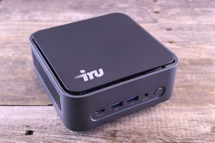 Computador compacto sobre uma mesa de madeira, com portas USB-C e outras conexões visíveis.
