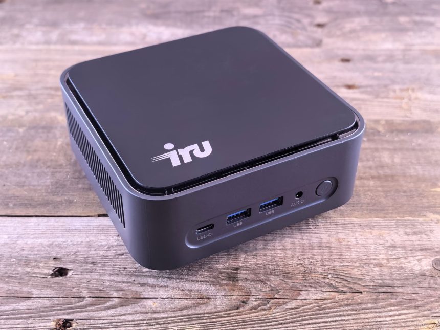 Computador compacto sobre uma mesa de madeira, com portas USB-C e outras conexões visíveis.