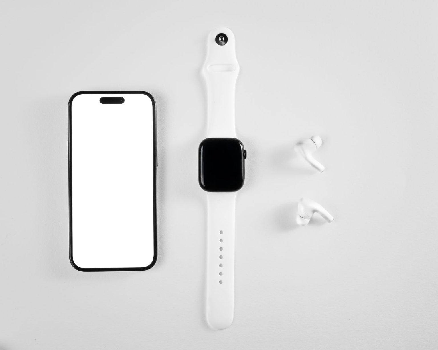 Smartphone, smartwatch e fones de ouvido sem fio dispostos sobre fundo branco.