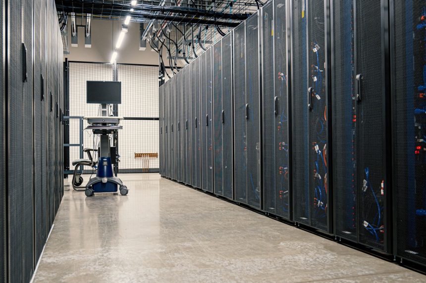 Armários metálicos com servidores, dispositivos de rede e cabos em um datacenter moderno.
