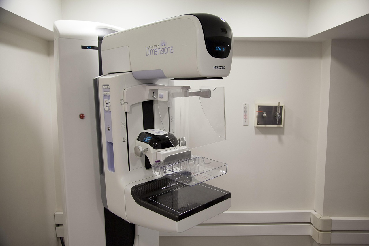 Equipamento de mamografia em ambiente hospitalar, acompanhado por uma profissional de saúde.